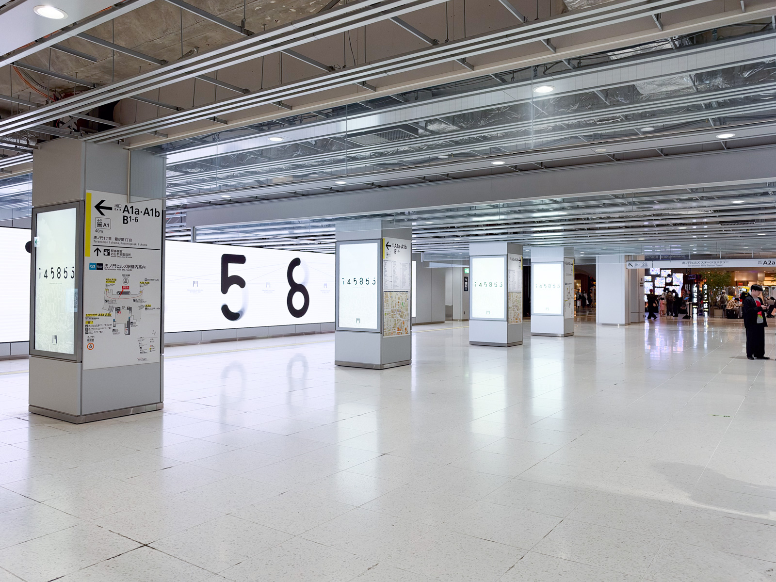 地下鉄コンコース(虎ノ門ヒルズ駅)。柱のデジタルサイネージに「56」の大きな数字。広告祭関連のビジュアルが並ぶ。遠くに出口への通路