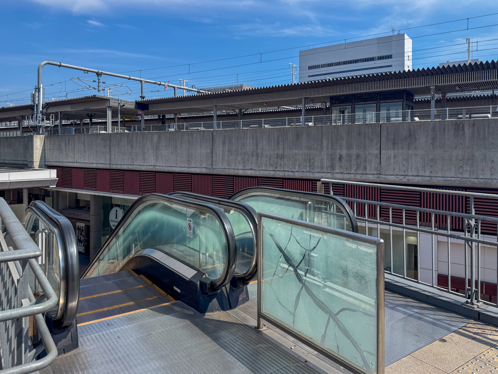 眺望デッキのエスカレーターと駅ホーム。コンクリートの高架構造が見える
